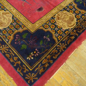 Ornate pink rug corner with elaborate navy blue and tan medallion borders rests on hardwood planks.