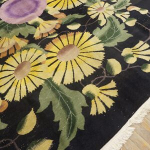 Yellow, green, and purple floral patterns cover a dark rug resting on light distressed wood planks.