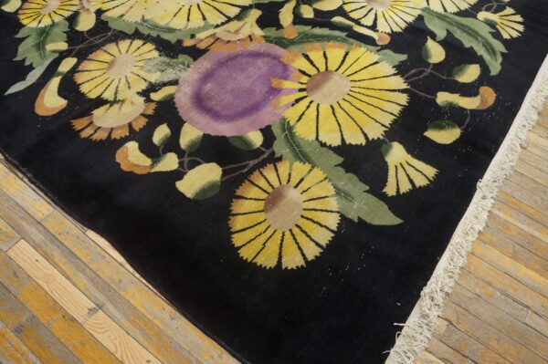 Black high-pile rug displays yellow, purple, and green floral patterns on distressed wood flooring.