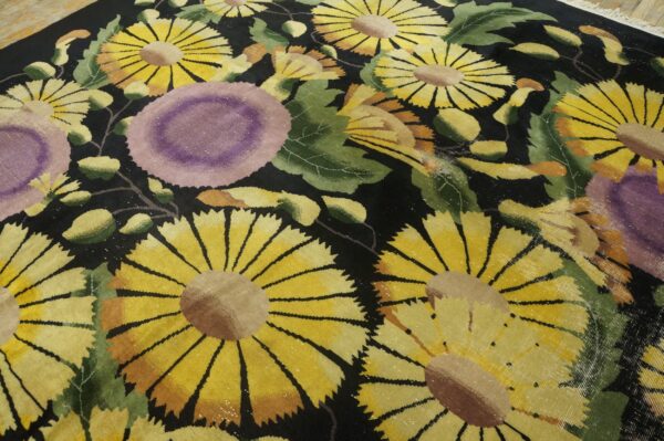 A high-pile black rug with large yellow, purple, and green florals resting on light wood flooring.