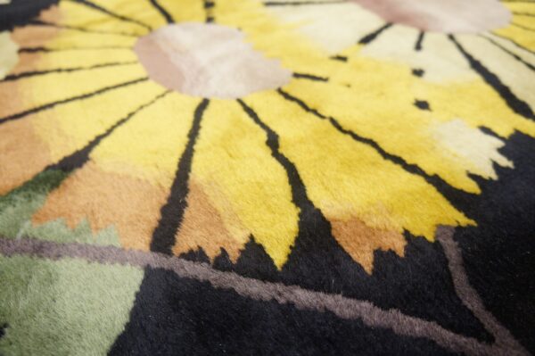 Close view of a plush yellow and beige floral rug with black outlining and green accents.