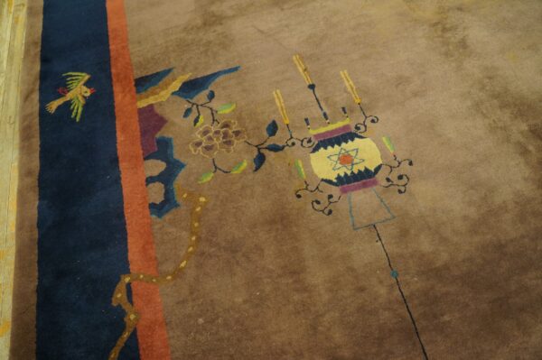 Tan rug with a navy, orange, and brown border, featuring floral, bird, and stylized lantern motifs.