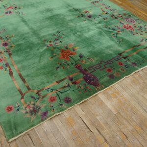 Lustrous green rug featuring a vibrant multicolored floral border on distressed light wood planks.