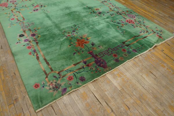 Lustrous green rug featuring a vibrant multicolored floral border on distressed light wood planks.