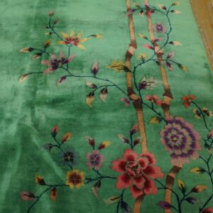 Green high-pile rug with a vibrant floral and bamboo pattern visible on distressed wooden floors.