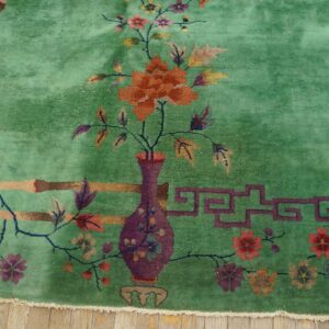 High-pile emerald green rug featuring a detailed floral pattern, including a vase and bamboo motifs, on wood flooring.