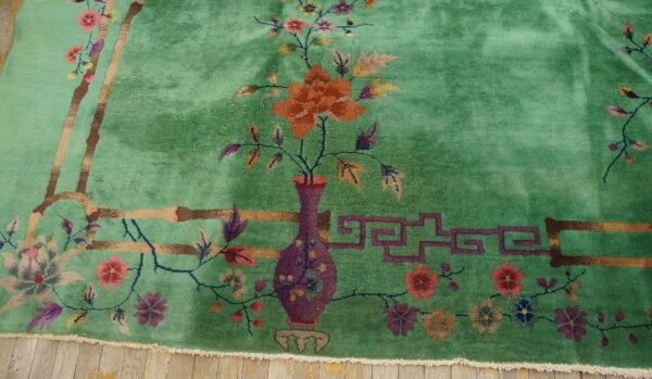 High-pile emerald green rug featuring a detailed floral pattern, including a vase and bamboo motifs, on wood flooring.