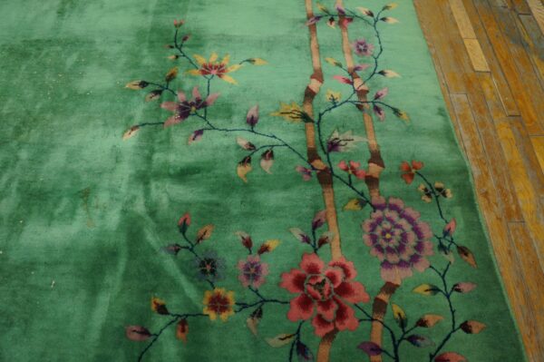 Medium-pile green rug displays colorful floral motifs and brown bamboo on rustic wood planks.