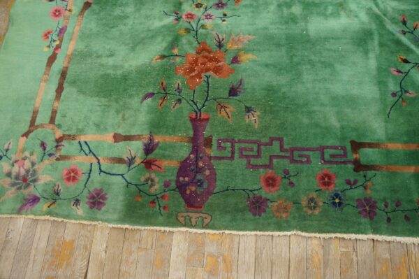 Mint green plush rug with an orange flower vase and bamboo patterns on light distressed wood.