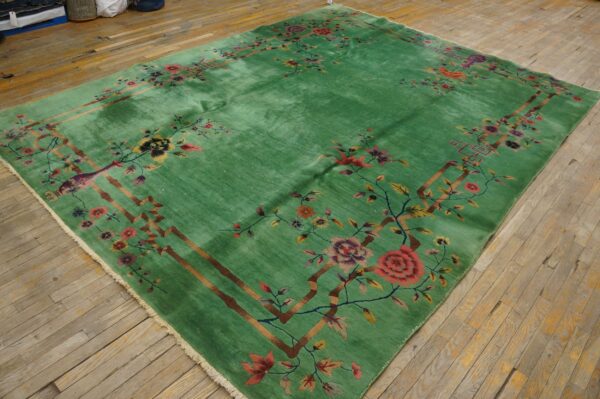 High-sheen green rug featuring a detailed border of multicolored flowers and brown branches on distressed wood planks.