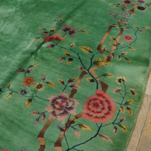 Bright green plush rug with colorful large-scale floral and branch designs on a light wooden floor.