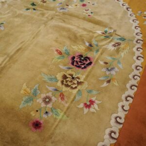 Golden rug with scattered multicolored floral bouquets and a decorative cloud border, visible over wood flooring.