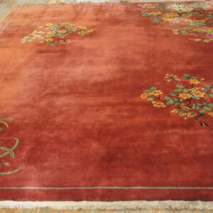 Large terra cotta rug featuring scattered yellow, pink, and green floral clusters on wood plank flooring.