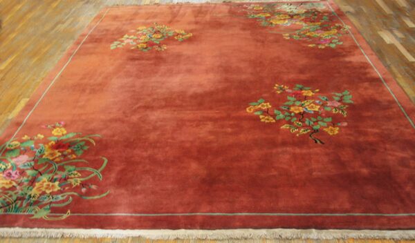 Large terra cotta rug featuring scattered yellow, pink, and green floral clusters on wood plank flooring.