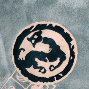 A soft light teal rug features a central dark teal and cream stylized circular medallion.