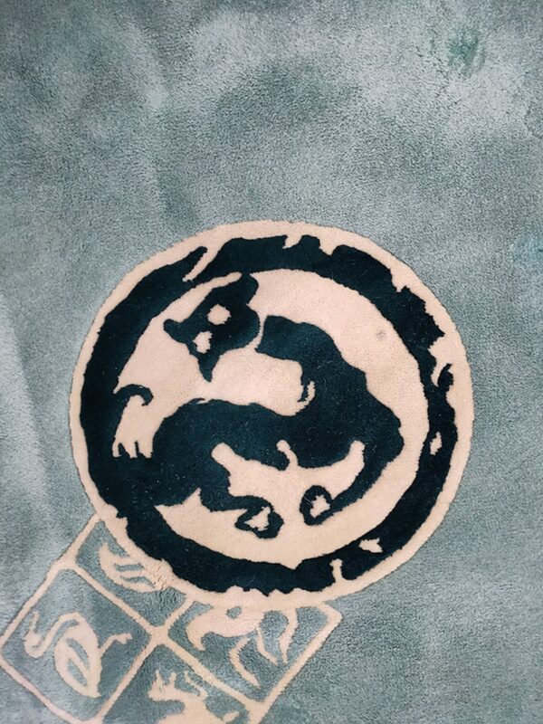 A soft light teal rug features a central dark teal and cream stylized circular medallion.