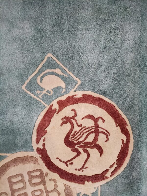 Teal rug with overlapping circles and diamonds featuring off-white and burgundy bird patterns.