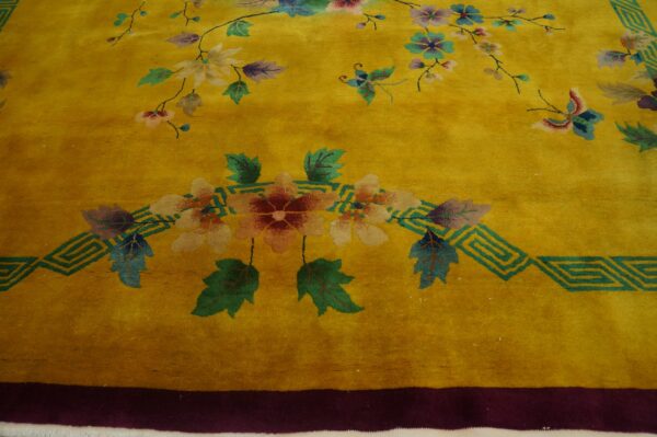 Golden yellow plush rug with multicolored florals, butterflies, and a teal geometric fretwork border.