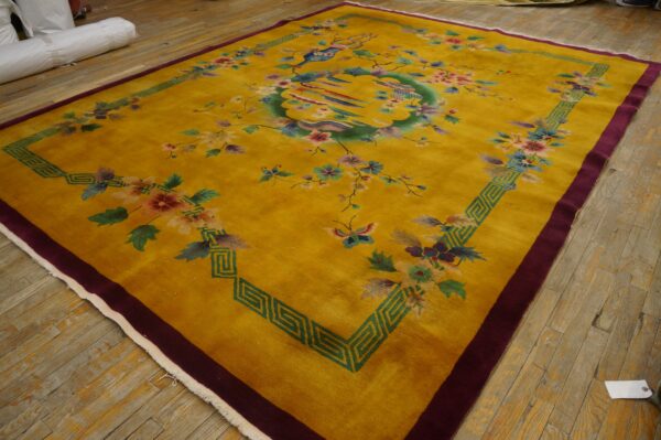Saffron yellow rug featuring a colorful central bird and floral pattern with deep green and maroon borders on wood floors.