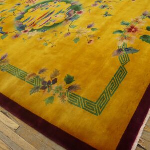 A bright yellow rug with colorful floral and medallion patterns, bordered in burgundy, rests on wood floors.