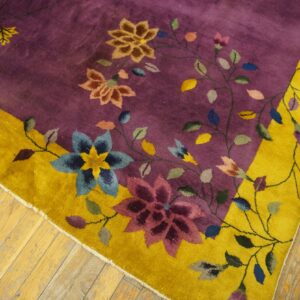 Plush purple rug featuring colorful scrolling floral designs and a wide golden yellow border on wood flooring.