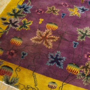 Purple field rug with a bright yellow border and large colorful leaves and vines on hardwood.