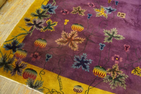 Purple field rug with a bright yellow border and large colorful leaves and vines on hardwood.