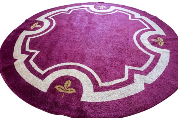 A round, purple plush rug featuring an off-white decorative medallion and small gold leaf accents.