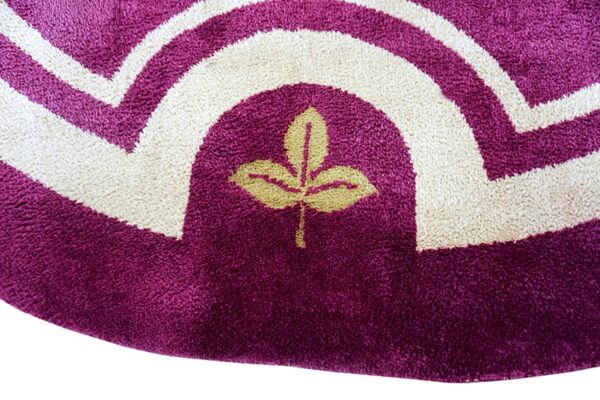 Deep purple, cream, and gold high-pile rug featuring curved geometric bands and a central leaf design.