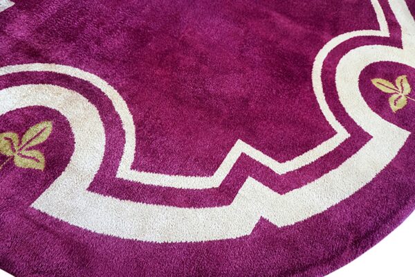 Close-up of a magenta high-pile rug detail featuring thick cream geometric borders and small golden leaf elements.
