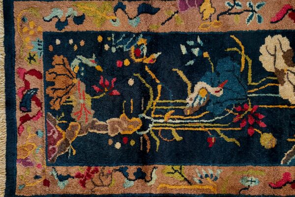 Close-up of a high-pile rug featuring a navy blue field and brown border with detailed multi-colored floral motifs.
