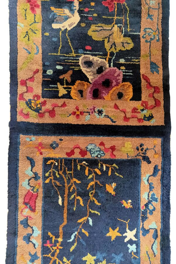 Dark navy high-pile rug with tan borders framing colorful stylized motifs of birds and foliage.