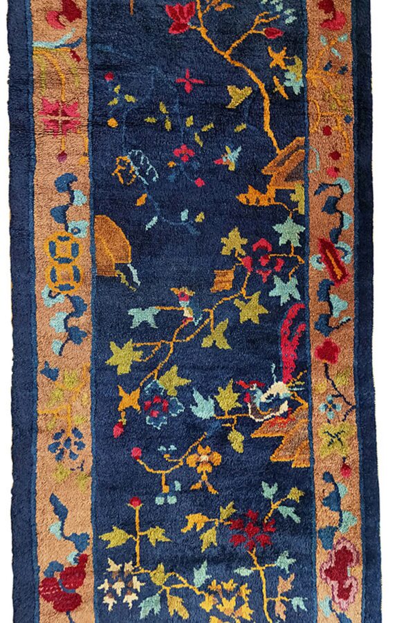 Vertical view of a high-pile navy runner featuring multicolored floral vines and a thick tan border.