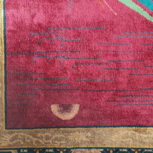 Detail shot of a magenta rug with colorful abstract lines, bordering a brown and dark geometric floral pattern.
