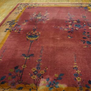 Rose rug featuring blue and yellow botanical designs, with a tan and mustard border on light wood flooring.