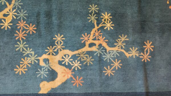 Teal rug with a stylized gold branch pattern and scattered orange and pale blue flowers.