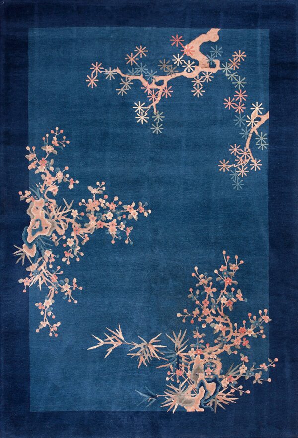 A deep indigo rug bordered by dark navy features scattered pink and peach flowering branches.