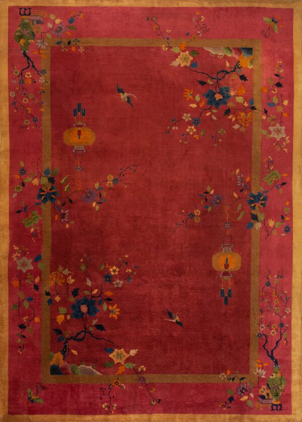 Crimson rug with gold border displaying stylized floral branches, birds, and hanging yellow lanterns.