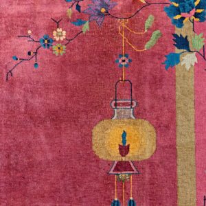 High-pile pink rug detail featuring a yellow lantern and blue flowers alongside a vertical gold stripe border.