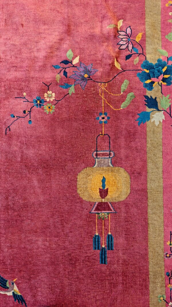 High-pile pink rug detail featuring a yellow lantern and blue flowers alongside a vertical gold stripe border.