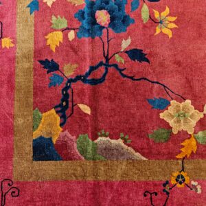 Magenta rug corner featuring gold border and vibrant blue, yellow, and green floral branch motifs.