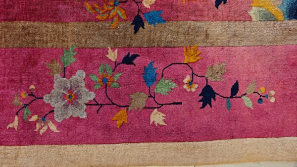 High-pile magenta rug detail with brown stripes and a flowing multicolor floral vine design.