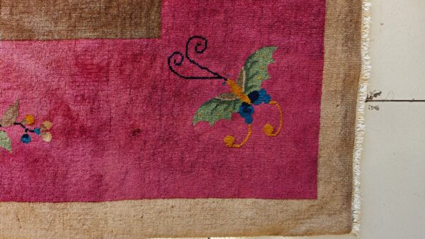 High-pile magenta rug with a green and blue butterfly pattern, lying on light distressed wood flooring.