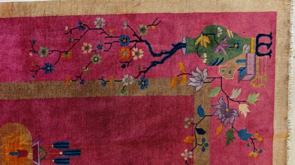 Deep pink rug detail shows a stylized green vase, multicolored blossoms, and a wide tan border.