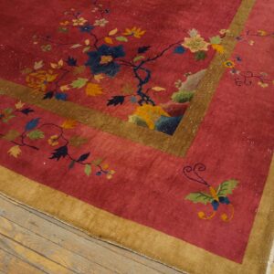 Low-pile red rug with scattered colorful florals and butterflies framed by gold borders on light wood flooring.