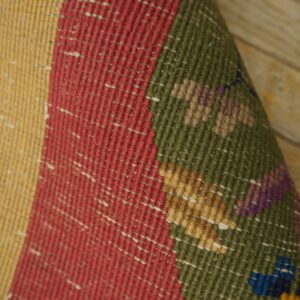 Detailed view of a flatweave rug featuring colorful bands and small geometric patterns on light wood flooring.