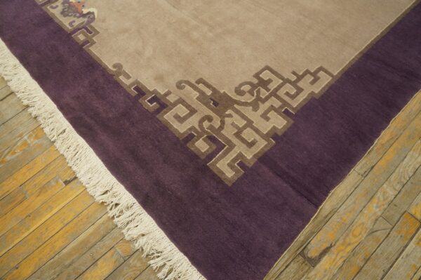 Tan rug corner with purple border, cream fringe, and brown geometric patterns on distressed wood floorboards.