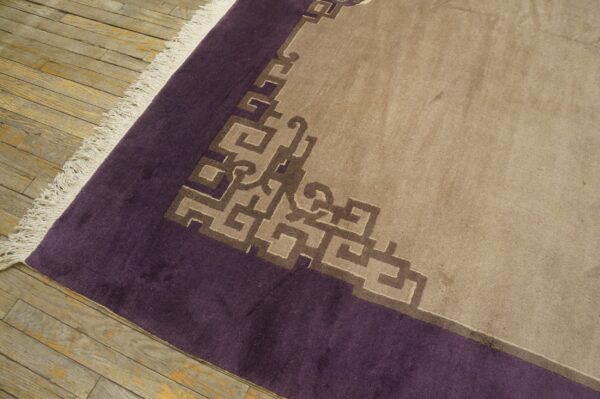 Beige low-pile rug with a dark purple border and geometric brown key pattern on distressed wood flooring.
