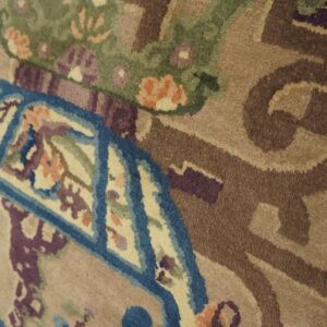 Detailed view of a tan cut pile rug with blue, green, purple, and peach stylized floral patterns.
