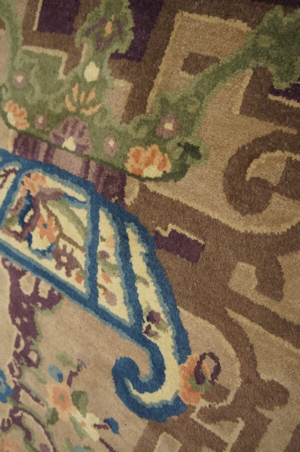Detailed view of a tan cut pile rug with blue, green, purple, and peach stylized floral patterns.